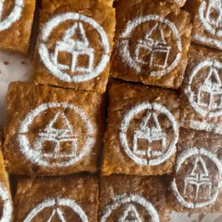 Several pastry pieces are sprinkled with a powdered sugar motif using a food stencil.