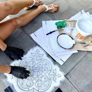 Eine Frau arbeitet auf dem Boden mit einem Schwamm und einer Kunststoffschablone