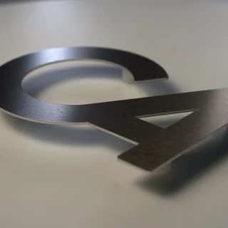 Logozuschnitt aus Aluminium mit Abstandshaltern im Butlerfinish