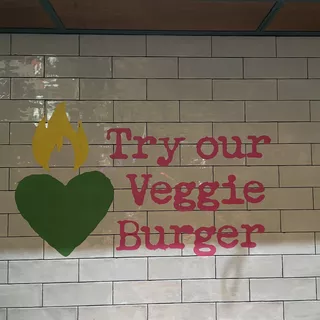 Try our Veggie Burger Schriftzug an einer Wand angebracht mit einer Lackierschablone