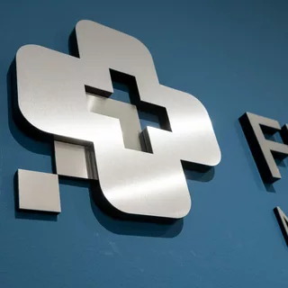 Ein individuelles Logo aus geschliffenem Edelstahl, verklebt auf einer blauen Wand