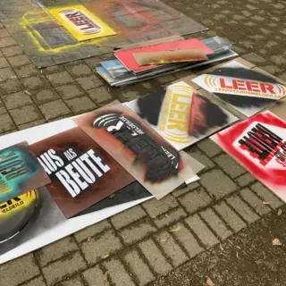 Mehrere bunt besprühte Werbeplakate liegen auf dem Boden