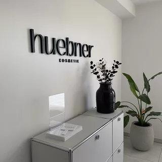 Schwarzer Schriftzug aus Hartschaum, an einer weißen Wand montiert und aus schrägem Winkel fotografiert.