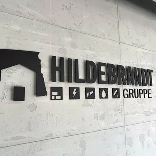 Hochwertiges schwarzes Acrylglaslogo angebracht mit Abstandshaltern und direkt verklebt