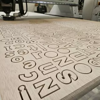 Individuelle Logos aus Holz werden aus einer Platte herausgefräst. Es entstehen Holzbuchstaben