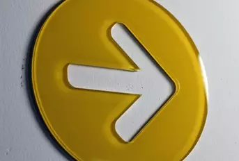 Gelbes Pfeilsymbol aus Acrylglas mit UV-Direktdruck, 6 mm, direkt auf eine Wand geklebt