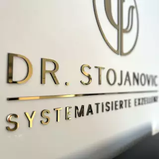 3D-Buchstaben und Logo aus gold poliertem Edelstahl auf Acrylglas, selbstklebend montiert.