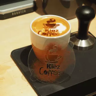 An individual cappuccino stencil leans against a cup with the finished design