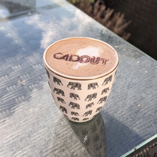 Cappuccinoschablone mit Cadout Logo in einer normalen Tasse