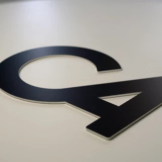 Firmenzeichen aus schwarz eloxiertem Aluminium direkt verklebt und individuell zugeschnitten.