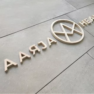 3D Holzbuchstaben sind auf einer Wand verklebt. Ein individuelles Logo befindet in der Mitte.