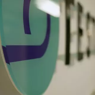 Acrylic glass circle that is digitally backprinted and another part of a logo in the background