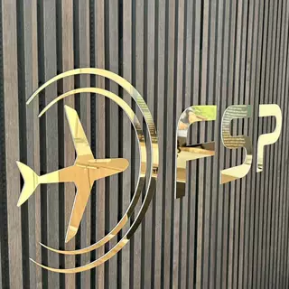 3D-Buchstaben und Logo aus gold poliertem Edelstahl auf Acrylglas, selbstklebend montiert.