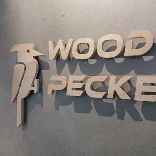 Holzbuchstaben und ein Holzvogel sind mit Abstandshaltern an einer Wand befestigt
