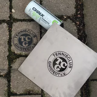 Logo Metallschablone aus Edelstahl inklusive Ergebnis auf Boden mit schwarzem Kreidespray 