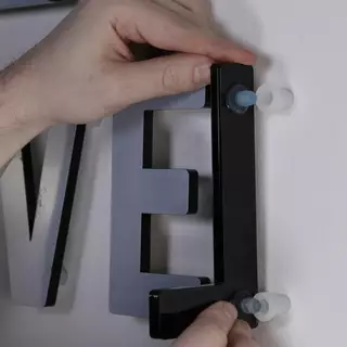 Schwarze 3D Buchstaben aus Acrylglas werden angebracht