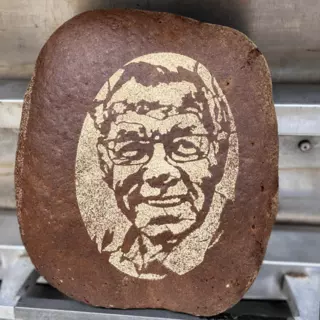 Ein dunkeles Brot verziert mit einem Gesicht aus Mehl - Backschablone